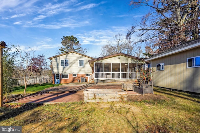 back of property featuring a lawn, a patio area, and a sunroom