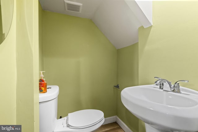 bathroom featuring wood-type flooring, toilet, lofted ceiling, and sink