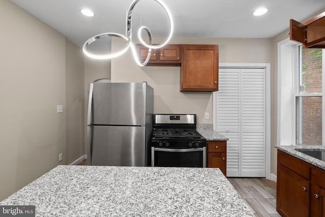 kitchen featuring light stone countertops, stainless steel appliances, and light hardwood / wood-style floors