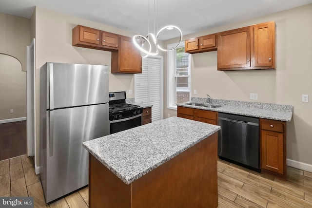 kitchen with sink, light hardwood / wood-style floors, decorative light fixtures, and appliances with stainless steel finishes