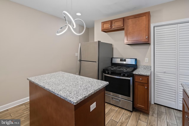 kitchen featuring hanging light fixtures, light hardwood / wood-style flooring, light stone countertops, a kitchen island, and stainless steel appliances