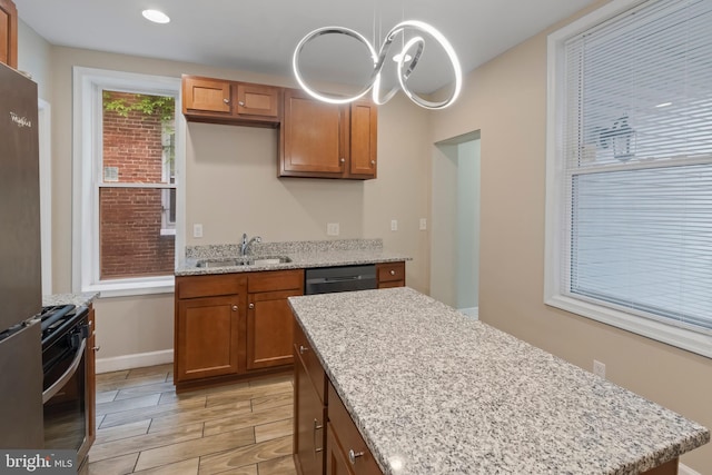 kitchen featuring decorative light fixtures, light stone counters, stainless steel appliances, and sink