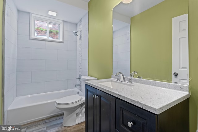 full bathroom with hardwood / wood-style floors, vanity, toilet, and tiled shower / bath