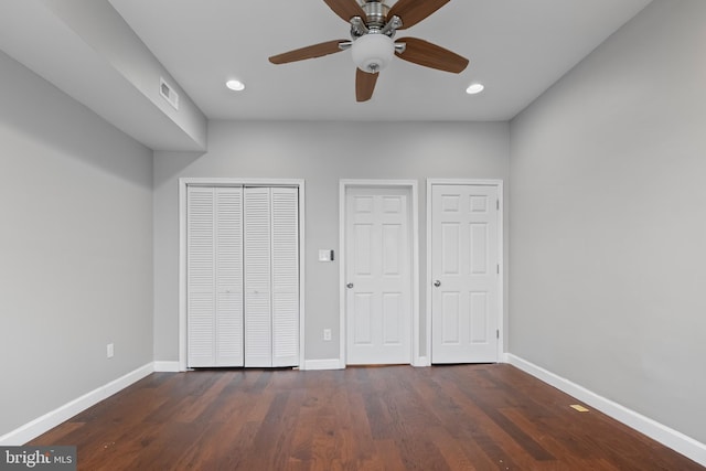 unfurnished bedroom with multiple closets, ceiling fan, and dark wood-type flooring