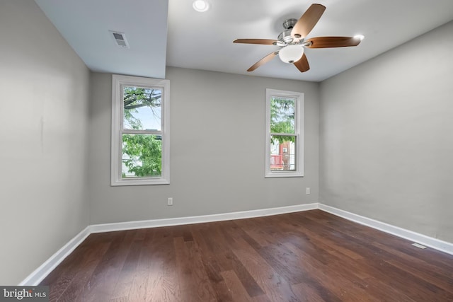 unfurnished room featuring a wealth of natural light, dark wood-type flooring, and ceiling fan