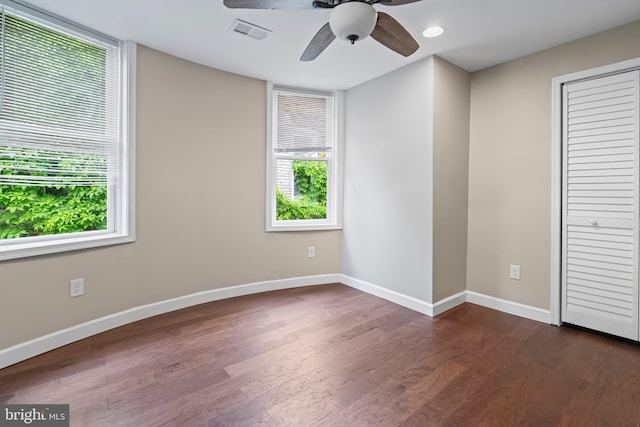 unfurnished bedroom featuring ceiling fan, dark hardwood / wood-style flooring, and multiple windows