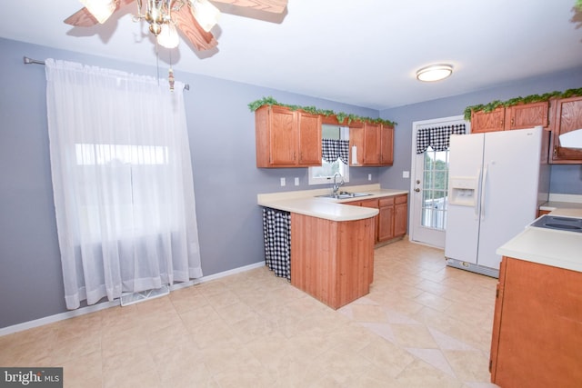 kitchen featuring kitchen peninsula, ceiling fan, white fridge with ice dispenser, and sink