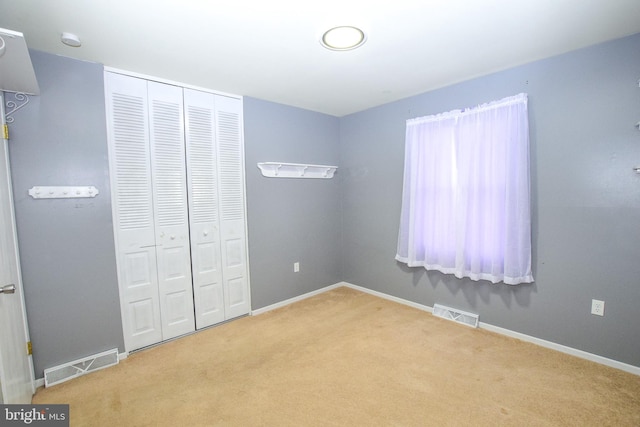 unfurnished bedroom with light colored carpet and a closet