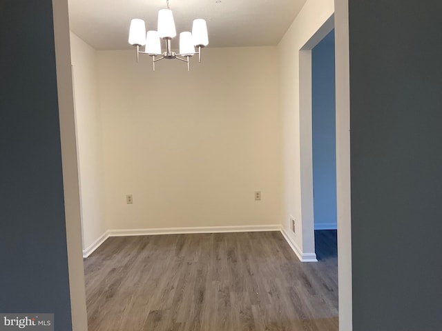 spare room featuring an inviting chandelier and wood-type flooring