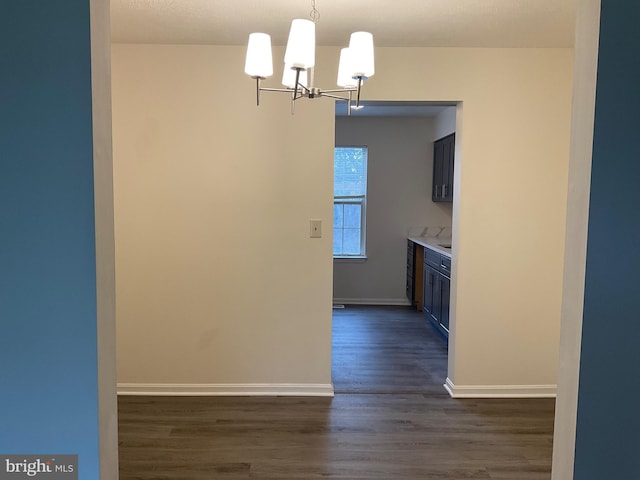 kitchen with dark wood-type flooring, pendant lighting, and a notable chandelier