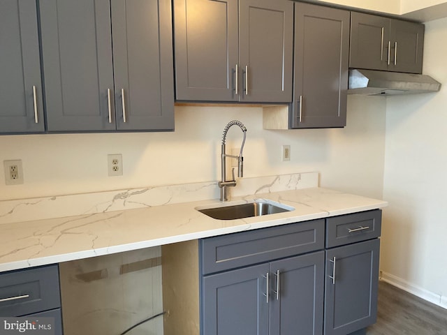 kitchen with light stone counters, gray cabinets, and sink