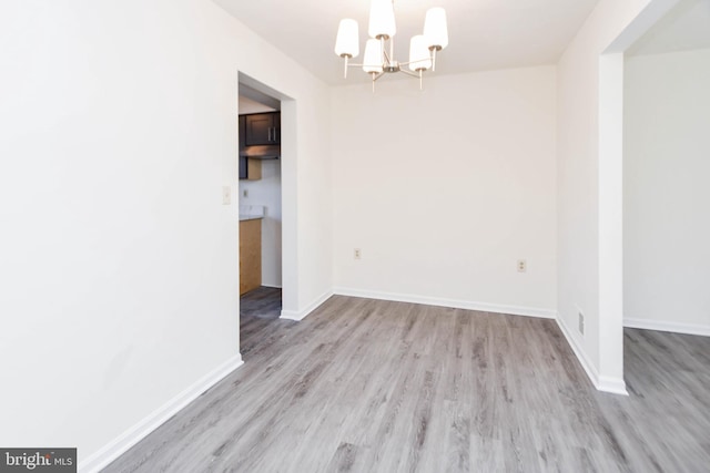 unfurnished dining area with a notable chandelier and light hardwood / wood-style flooring