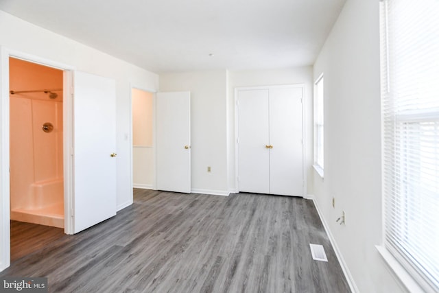 unfurnished bedroom with multiple windows, wood-type flooring, and a closet