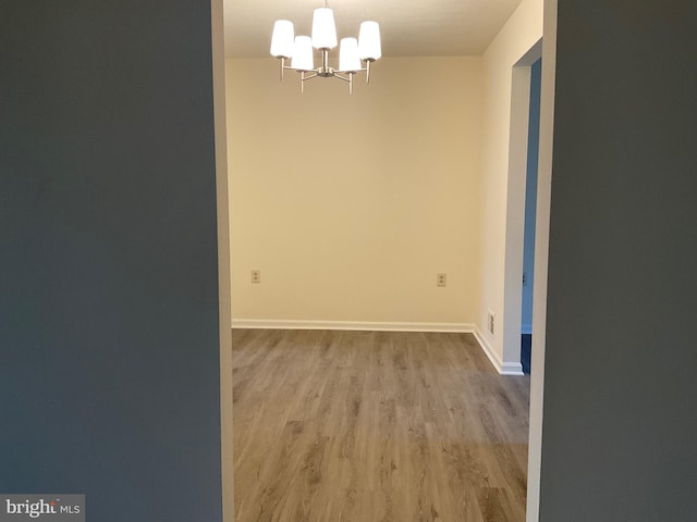 unfurnished room featuring light wood-type flooring and a chandelier