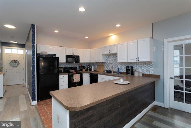 kitchen featuring kitchen peninsula, sink, white cabinets, and black appliances