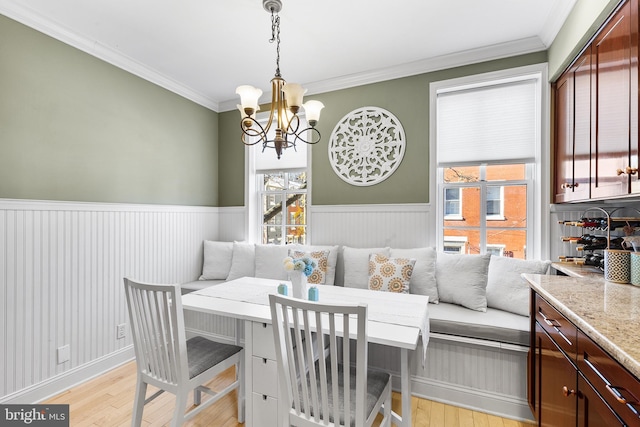 dining room with light wood-type flooring, breakfast area, a chandelier, and ornamental molding