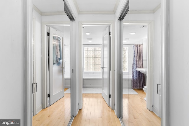 corridor with light hardwood / wood-style flooring and ornamental molding