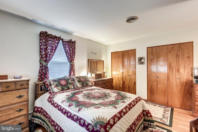 bedroom featuring two closets and light hardwood / wood-style floors