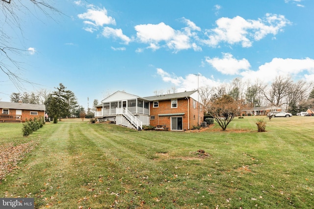 rear view of house featuring a yard and a sunroom