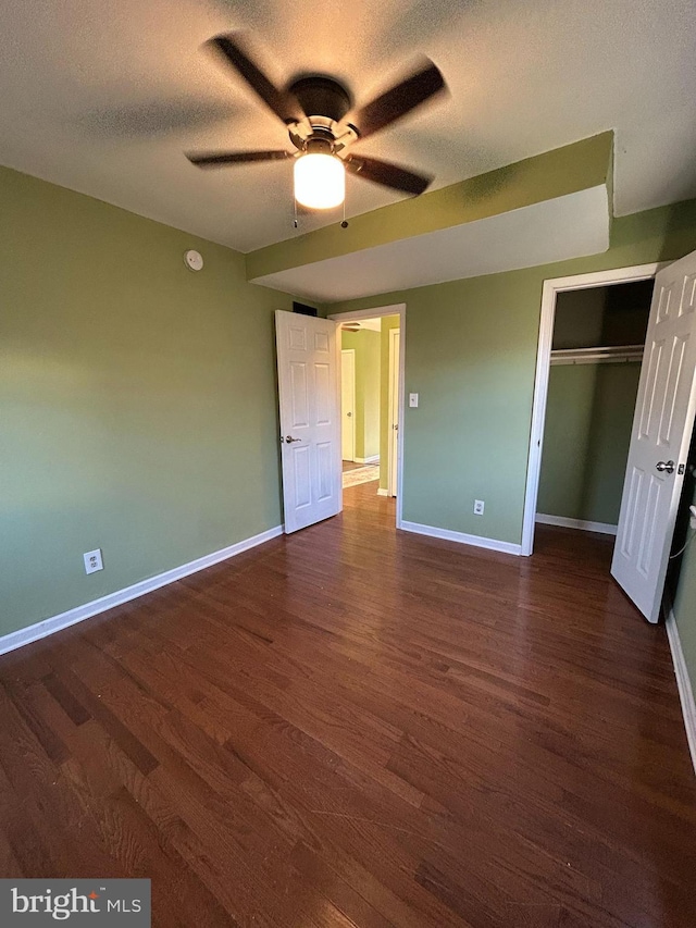 unfurnished bedroom featuring a textured ceiling, a closet, ceiling fan, and dark wood-type flooring