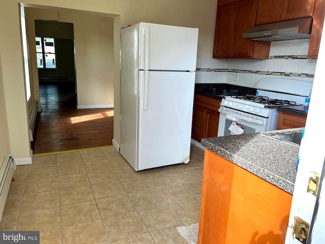 kitchen with light wood-type flooring, white appliances, a baseboard heating unit, and backsplash