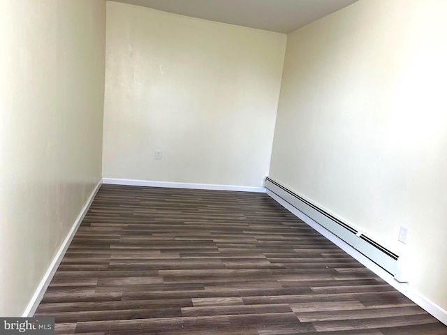 unfurnished room with dark hardwood / wood-style floors and baseboard heating