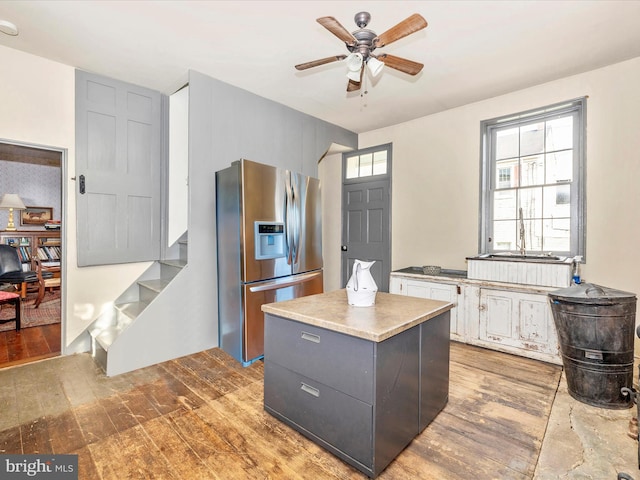 kitchen featuring a center island, wood-type flooring, sink, stainless steel fridge, and ceiling fan