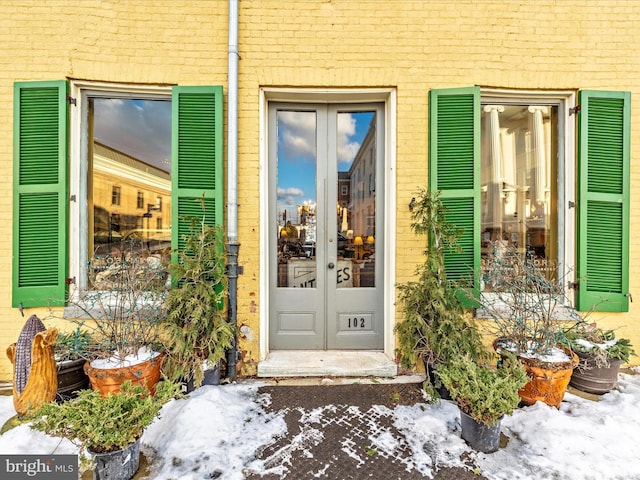 snow covered property entrance featuring french doors