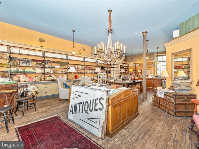 kitchen featuring hardwood / wood-style floors, decorative light fixtures, a chandelier, vaulted ceiling, and a center island with sink