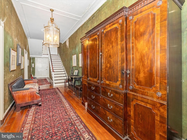 hall featuring dark hardwood / wood-style floors, ornamental molding, and an inviting chandelier