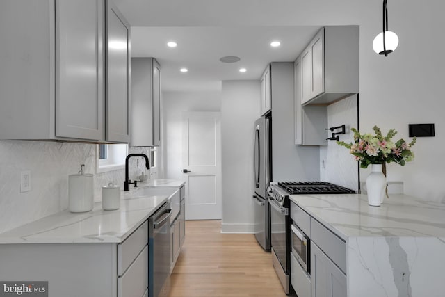 kitchen featuring sink, hanging light fixtures, gray cabinets, appliances with stainless steel finishes, and light hardwood / wood-style floors