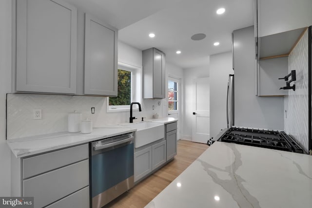 44 Sheridan St NE, Washington, DC 20011 - kitchen with stainless steel dishwasher, gray cabinets, backsplash, black gas range oven, and light wood finished floors