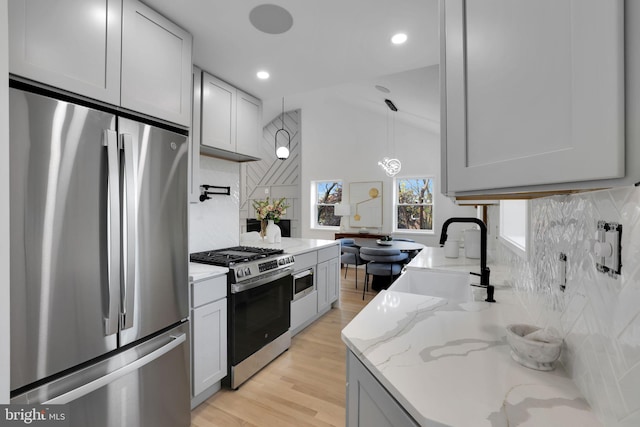 kitchen featuring appliances with stainless steel finishes, tasteful backsplash, light hardwood / wood-style flooring, and sink