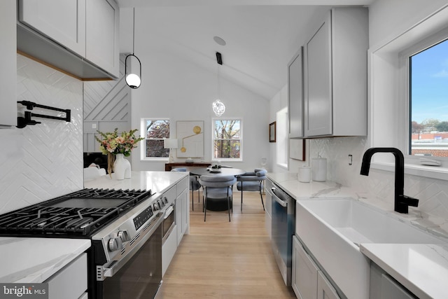kitchen featuring gray cabinetry, backsplash, stainless steel appliances, and a wealth of natural light