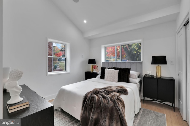bedroom featuring vaulted ceiling, light wood-type flooring, and a closet