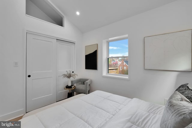 bedroom with hardwood / wood-style flooring, a closet, and vaulted ceiling