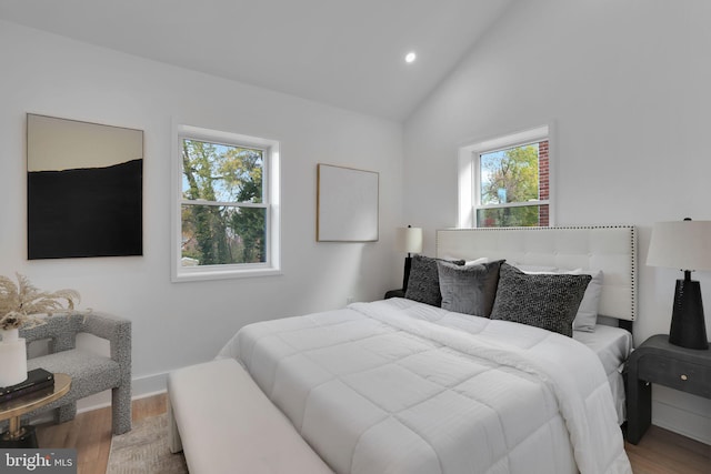 bedroom with high vaulted ceiling and wood-type flooring