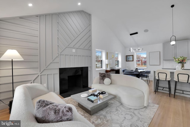 living room featuring lofted ceiling, a notable chandelier, and light wood-type flooring
