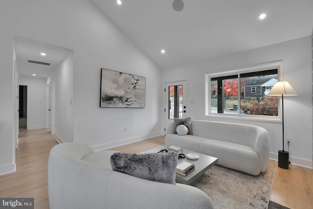 living room with light hardwood / wood-style flooring and high vaulted ceiling