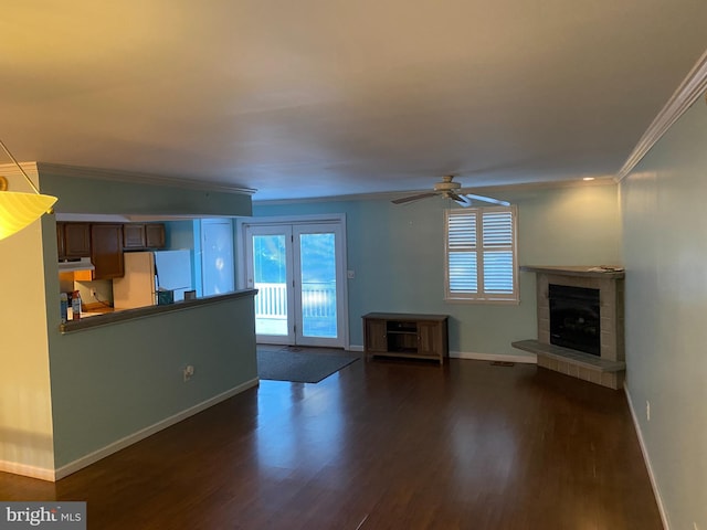 unfurnished living room with dark hardwood / wood-style floors, ceiling fan, ornamental molding, and a tiled fireplace