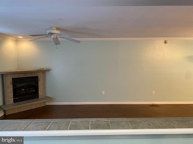 unfurnished living room featuring dark hardwood / wood-style floors, ceiling fan, crown molding, and a tile fireplace