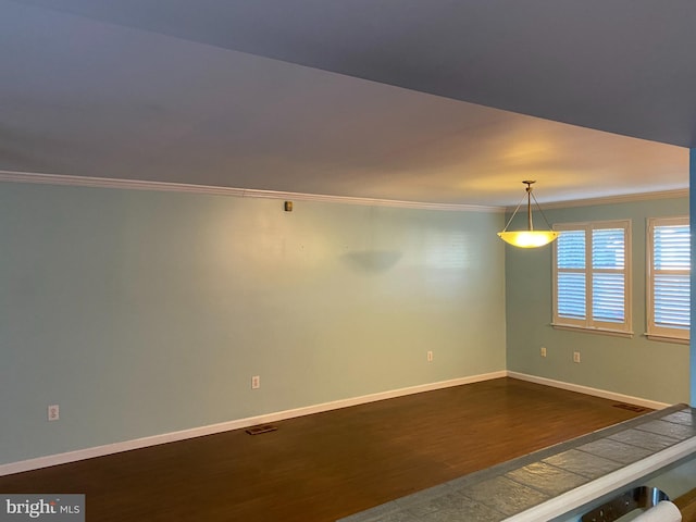 spare room with hardwood / wood-style floors and crown molding