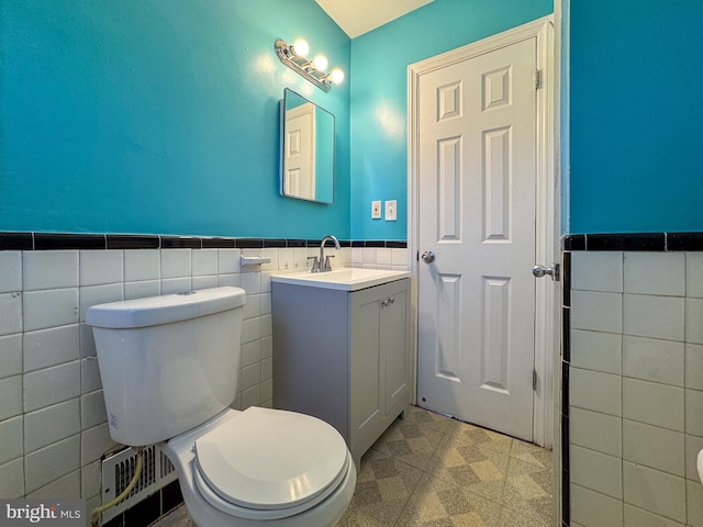 bathroom with vanity, toilet, and tile walls