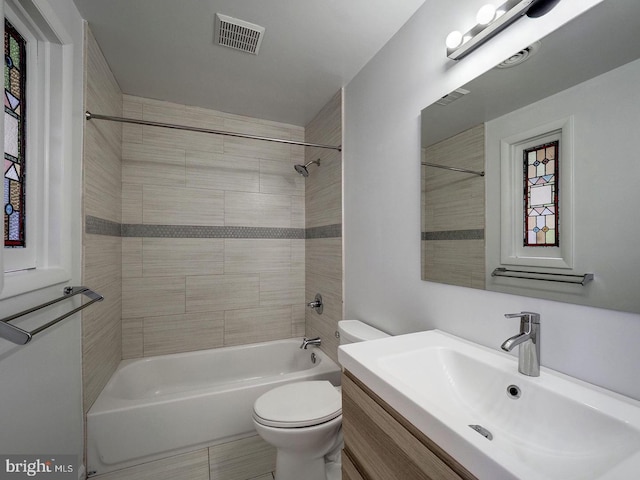 full bathroom featuring tiled shower / bath combo, toilet, and vanity