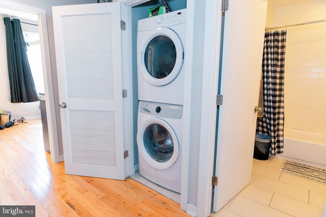 laundry room with stacked washer / dryer and light wood-type flooring