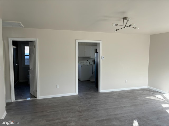 spare room featuring separate washer and dryer, an inviting chandelier, and dark wood-type flooring