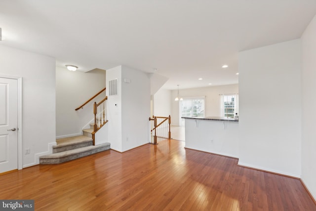 unfurnished living room featuring hardwood / wood-style floors and an inviting chandelier