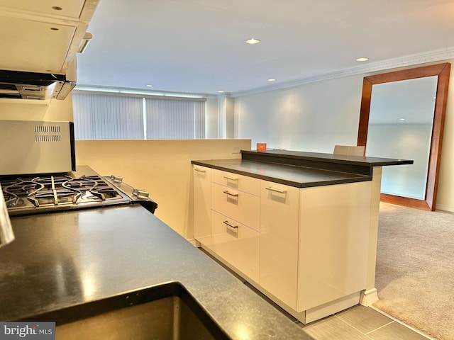 kitchen with white cabinets, light colored carpet, and ornamental molding