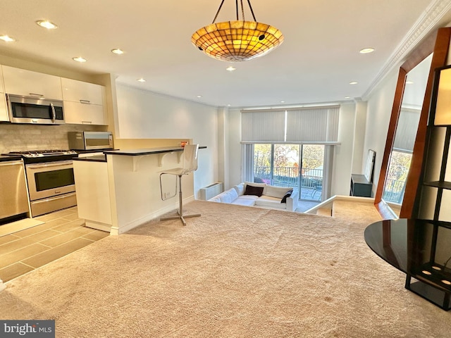 kitchen with white cabinetry, light colored carpet, pendant lighting, a breakfast bar, and appliances with stainless steel finishes