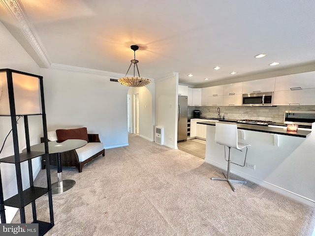 kitchen featuring crown molding, decorative backsplash, decorative light fixtures, white cabinetry, and stainless steel appliances